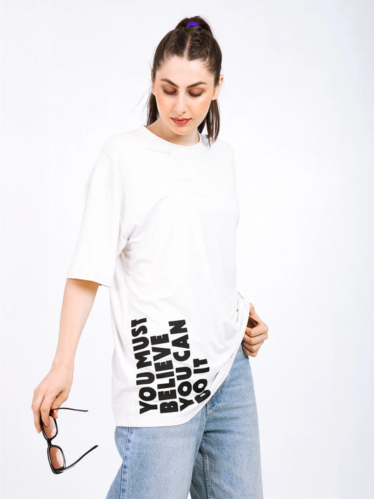 Woman modeling a white oversized bamboo T-shirt with motivational text and casual jeans.