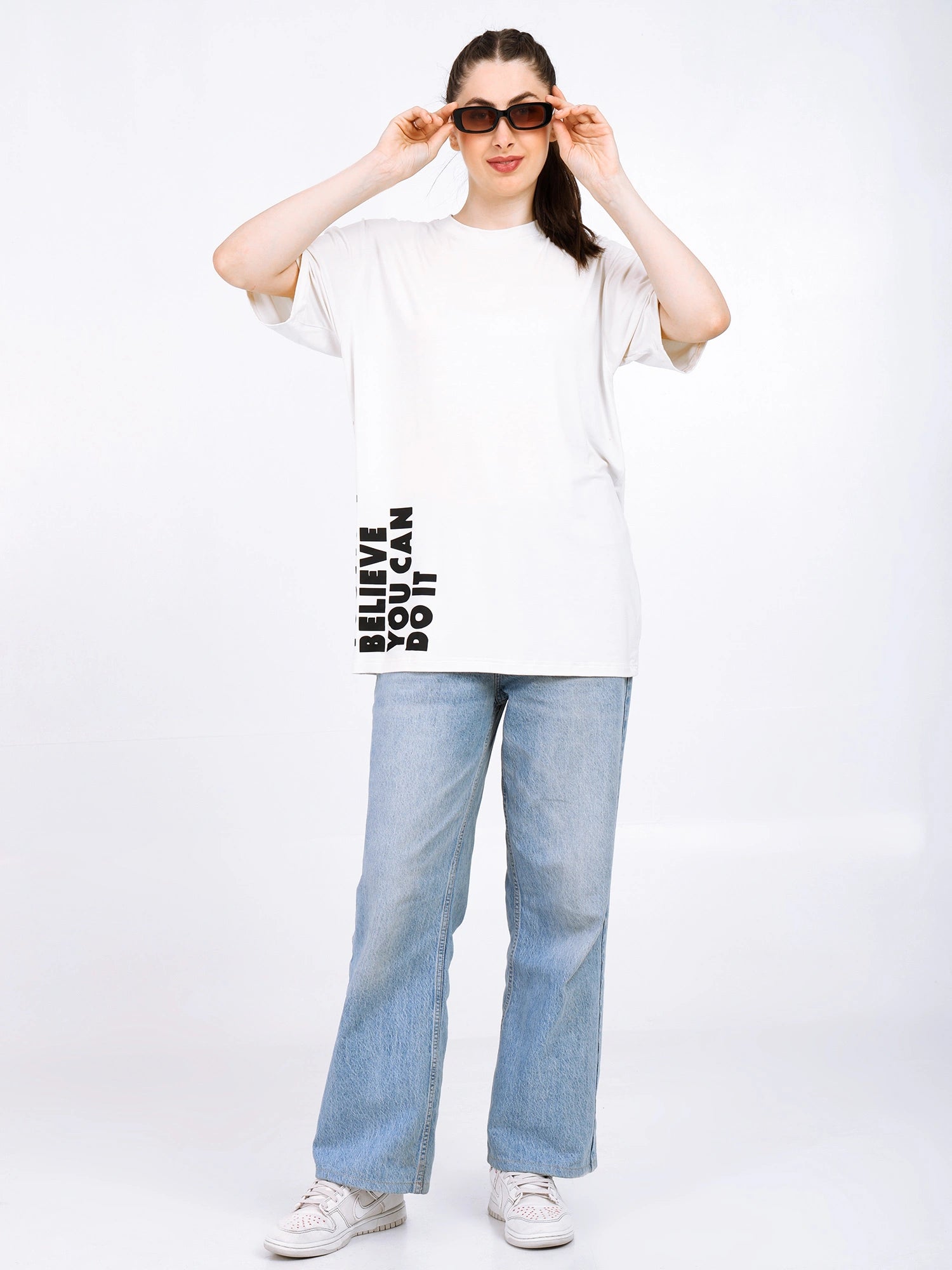 Model wearing Women Oversized Bamboo T-Shirt with graphic text, casual style, paired with light jeans and sunglasses.
