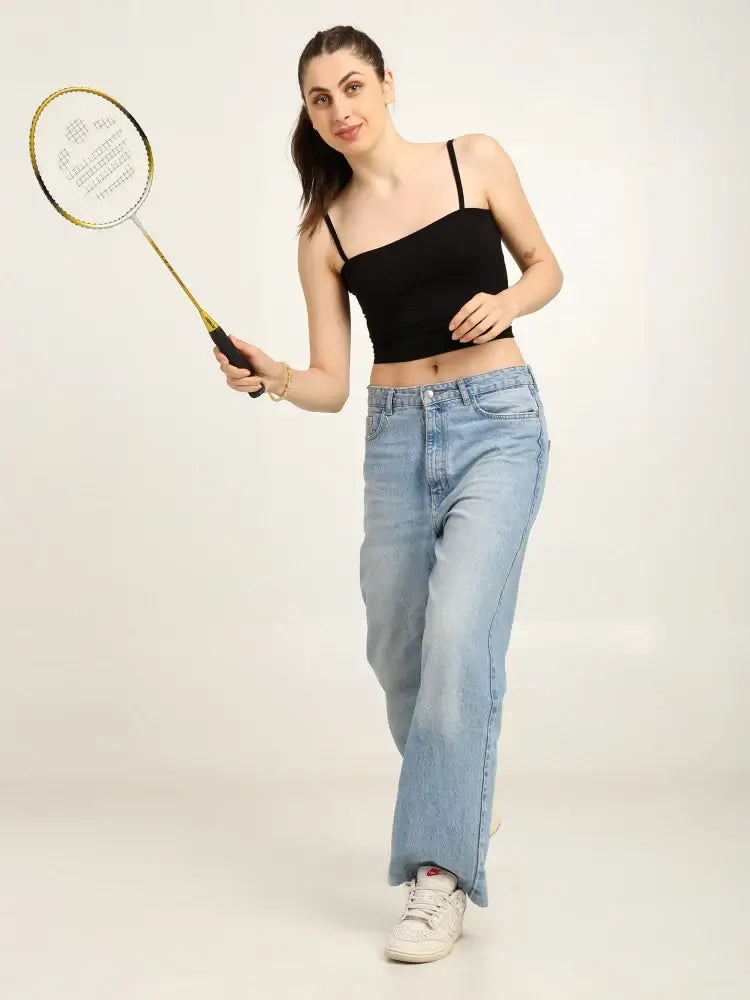 Gen Z woman in a bamboo tube top and jeans, playing badminton, showcasing effortless and sustainable fashion.