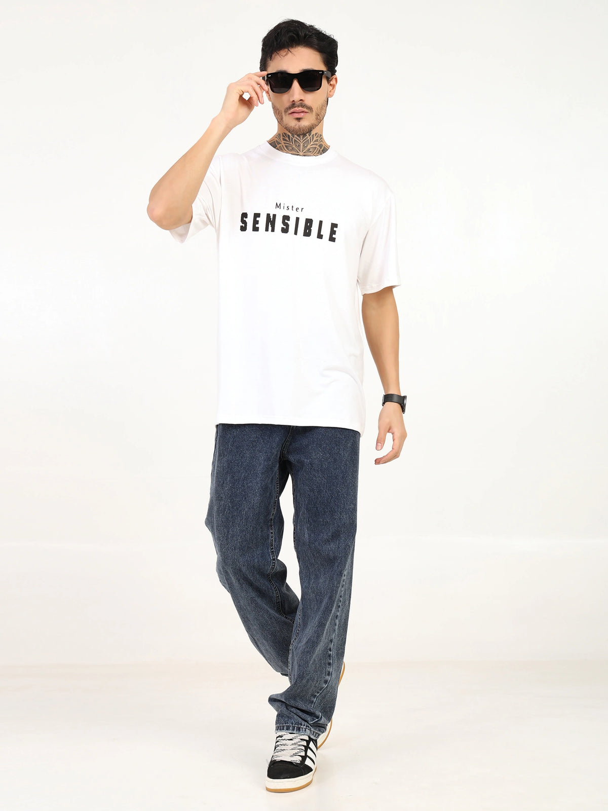 Men's oversized bamboo T-shirt in white, featuring 'SENSIBLE' graphic, paired with blue jeans and sneakers.