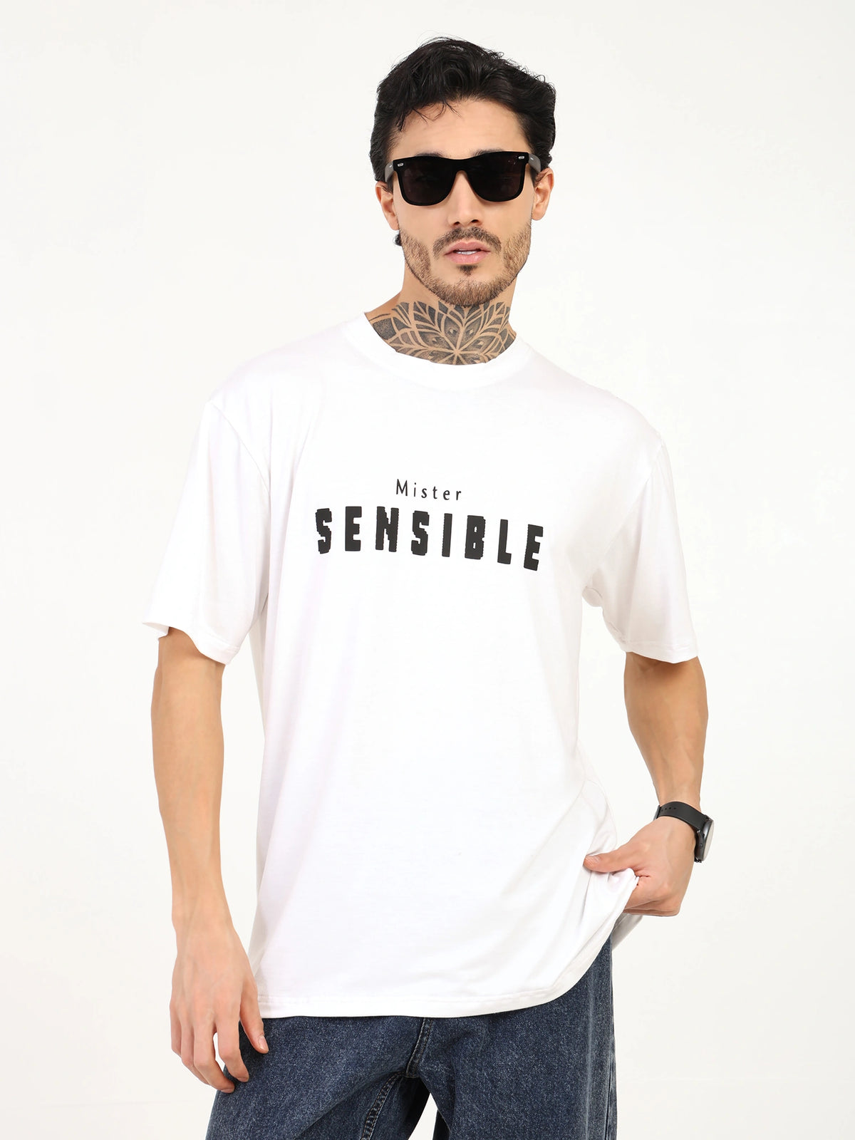 Men's white oversized t-shirt with "Mister SENSIBLE" print, styled with sunglasses and casual denim.