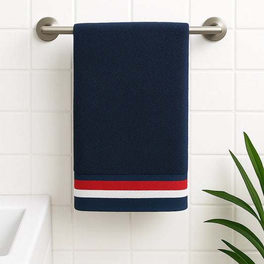 Navy blue towel with red and white stripes hanging on a towel rack against a tiled wall.