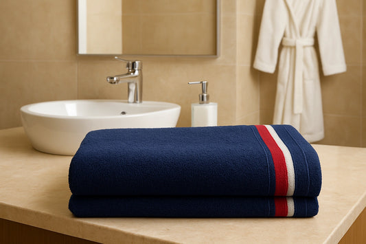 Folded blue towel with red and white stripes on a bathroom counter, with a sink and mirror in the background.
