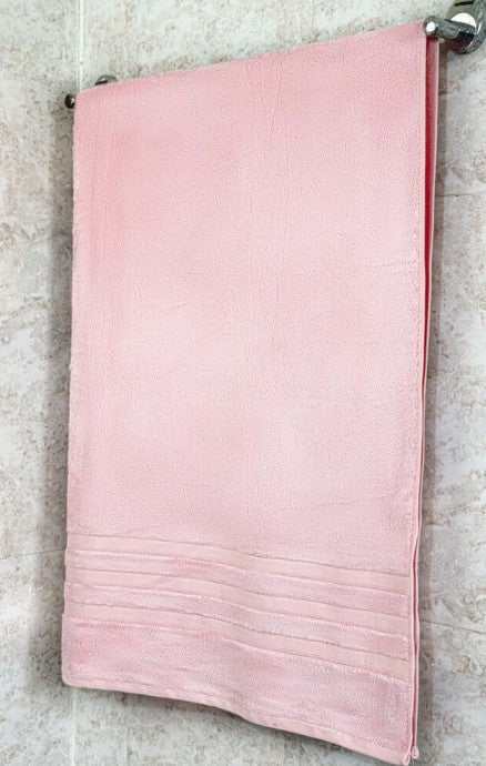 Soft pink bamboo bath towel hanging on a towel rack, highlighting its luxurious eco-friendly design.