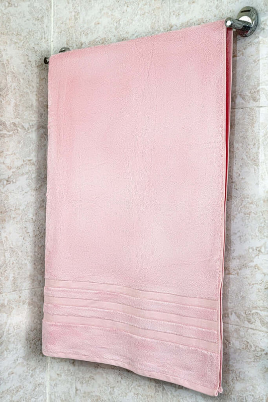 Soft pink bamboo bath towel hanging on a towel rack, highlighting its luxurious eco-friendly design.