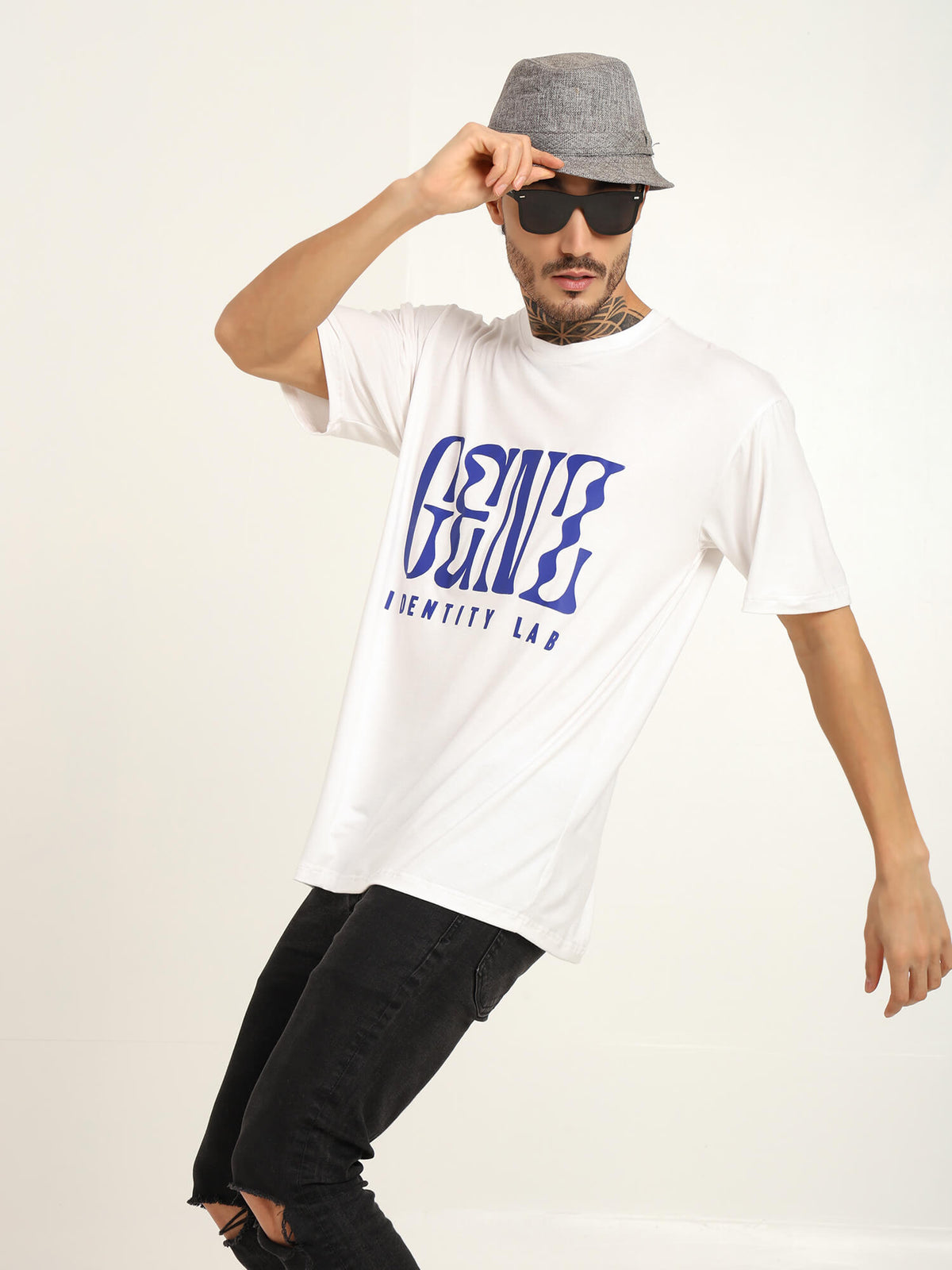 Man modeling a white oversized t-shirt with blue graphic print, wearing sunglasses and a gray hat.