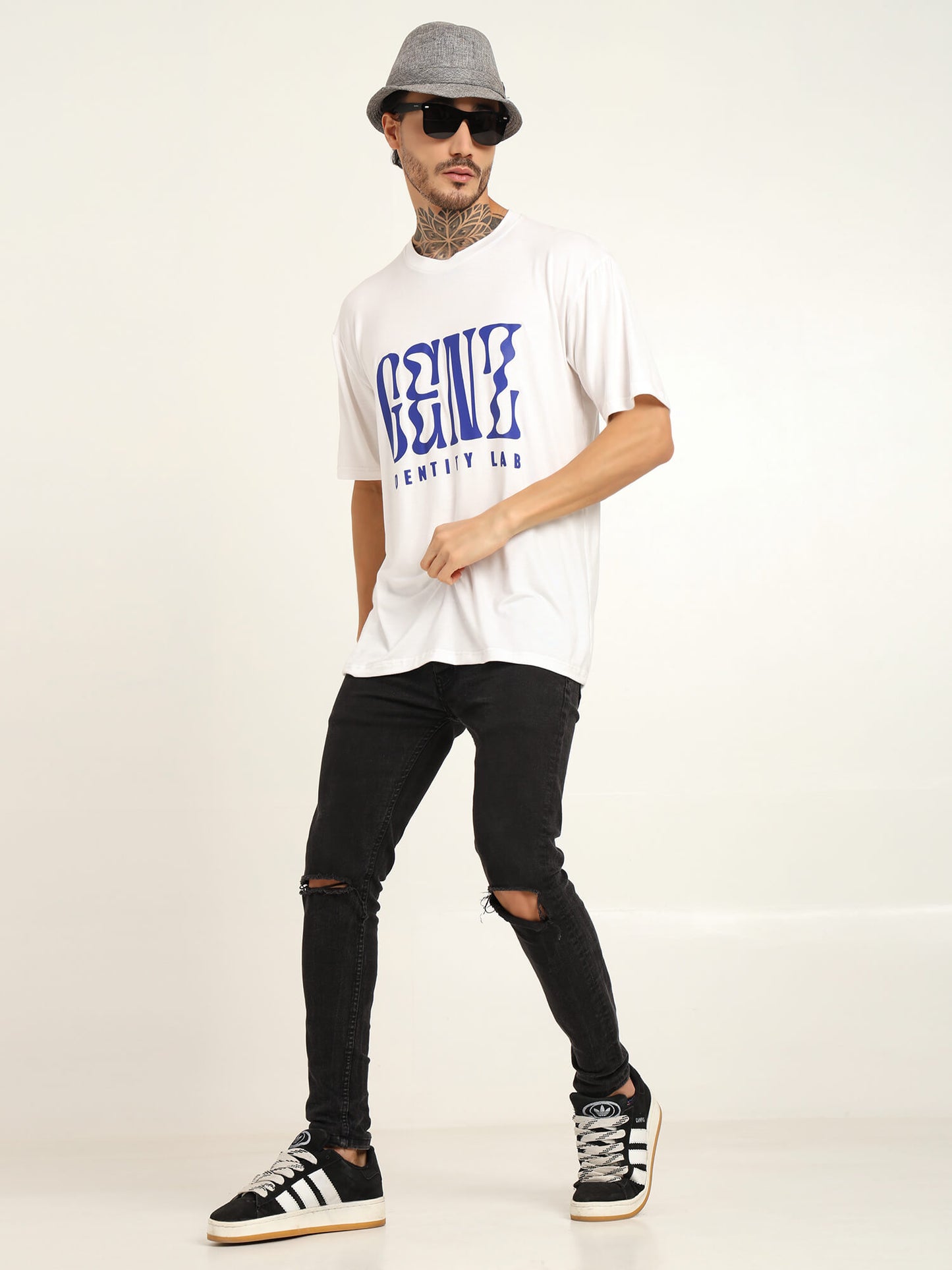 Man wearing oversized bamboo T-shirt with graphic design, black ripped jeans, and stylish sneakers, showcasing streetwear style.