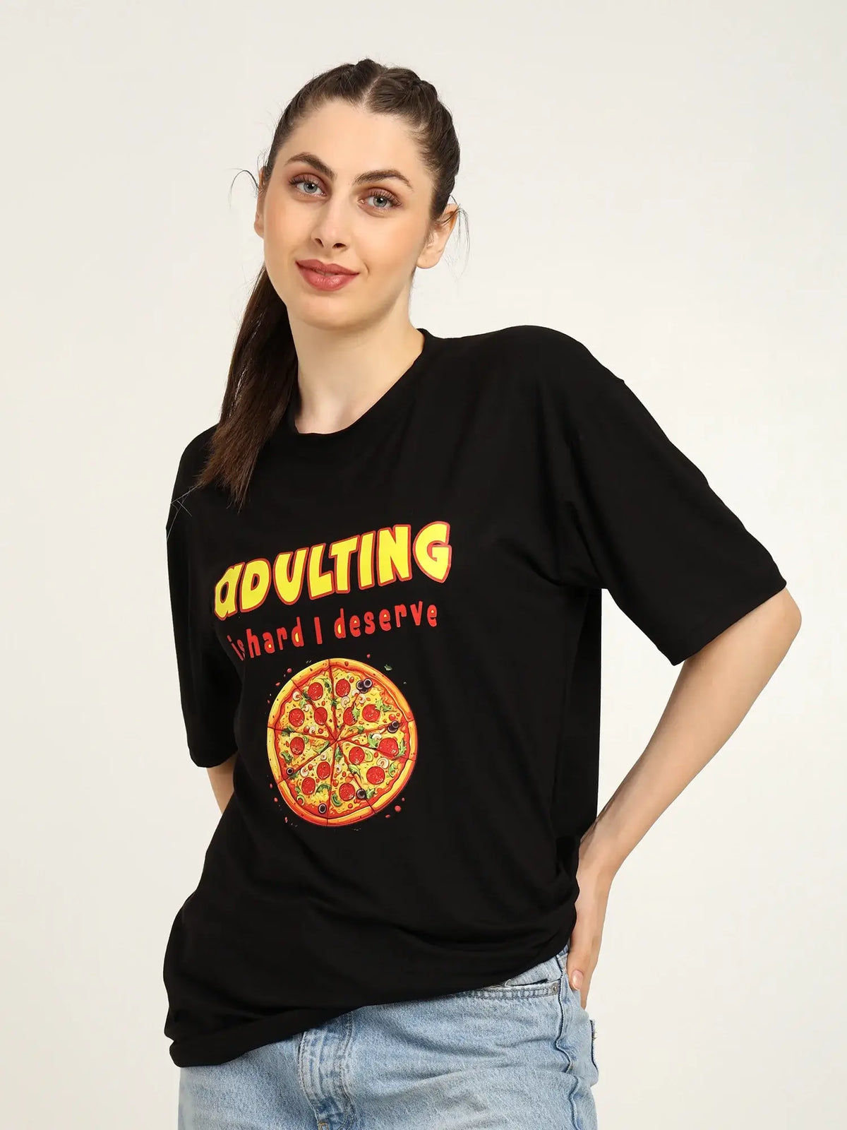 Woman wearing a black t-shirt with a pizza graphic and text on a plain background