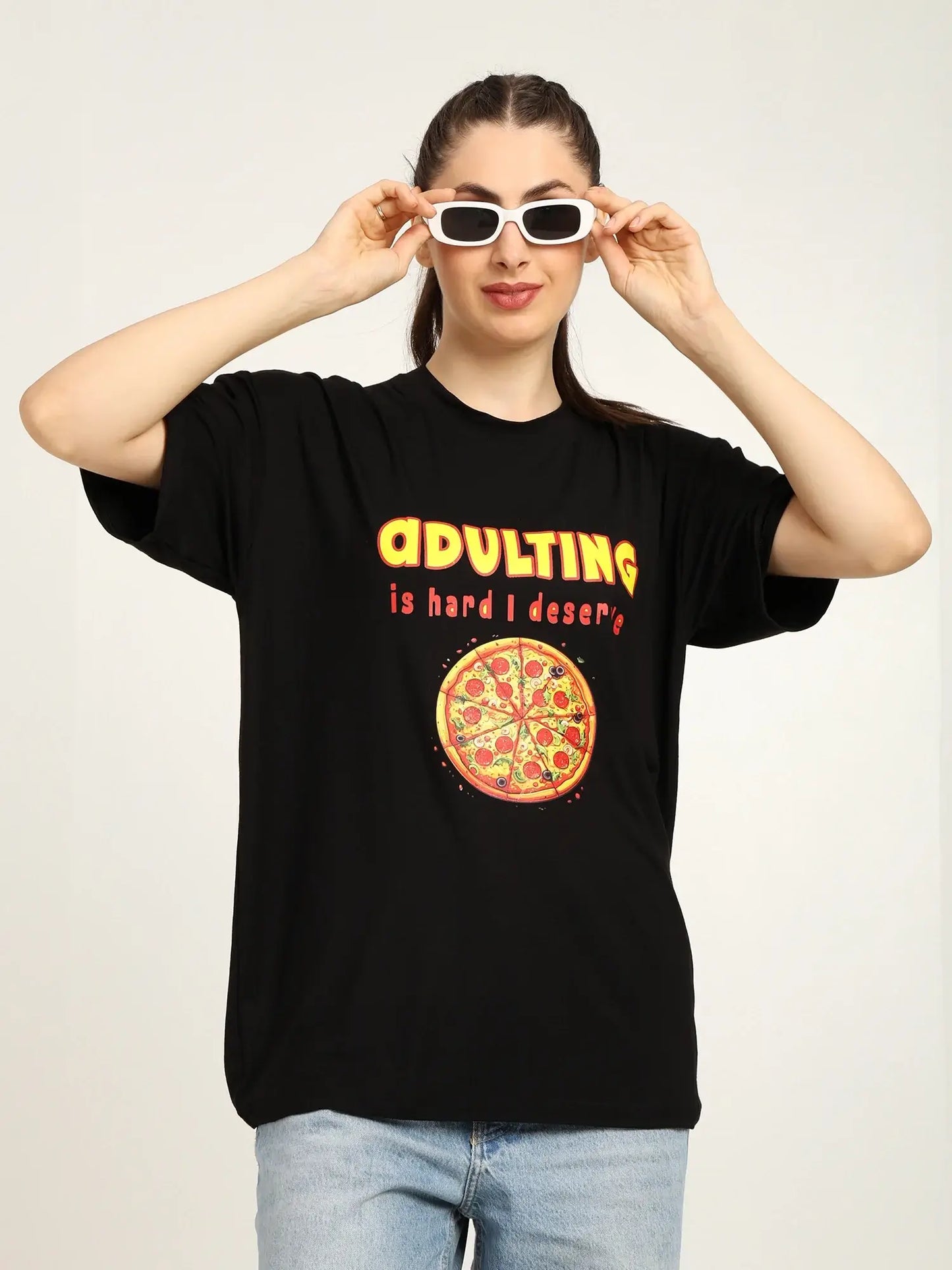 Person wearing a black t-shirt with a pizza graphic and text, holding sunglasses.