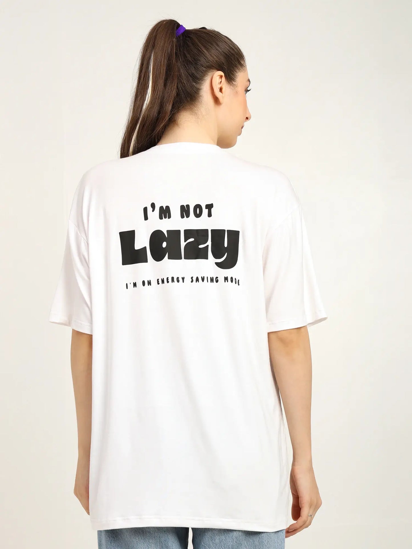 Back of a woman wearing an oversized white T-shirt with quirky text 'I'm not lazy' printed on it.