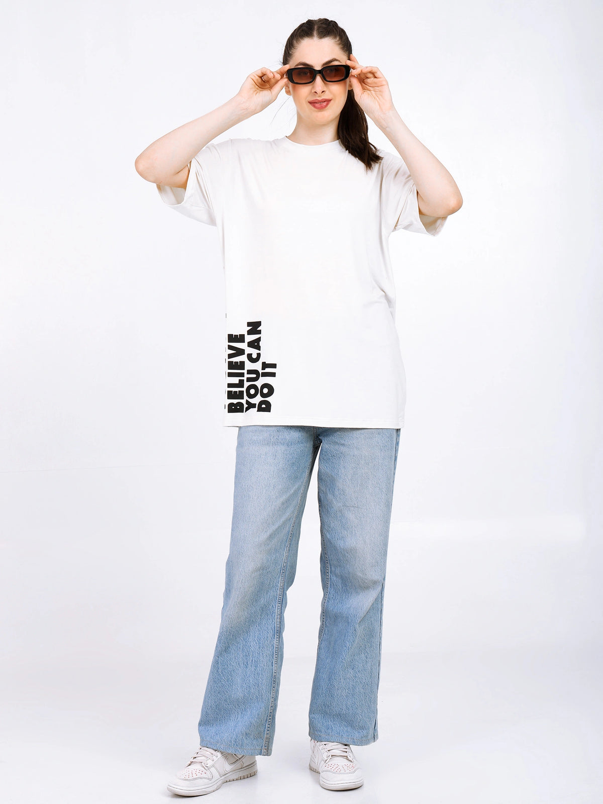 Model wearing Women Oversized Bamboo T-Shirt with graphic text, casual style, paired with light jeans and sunglasses.