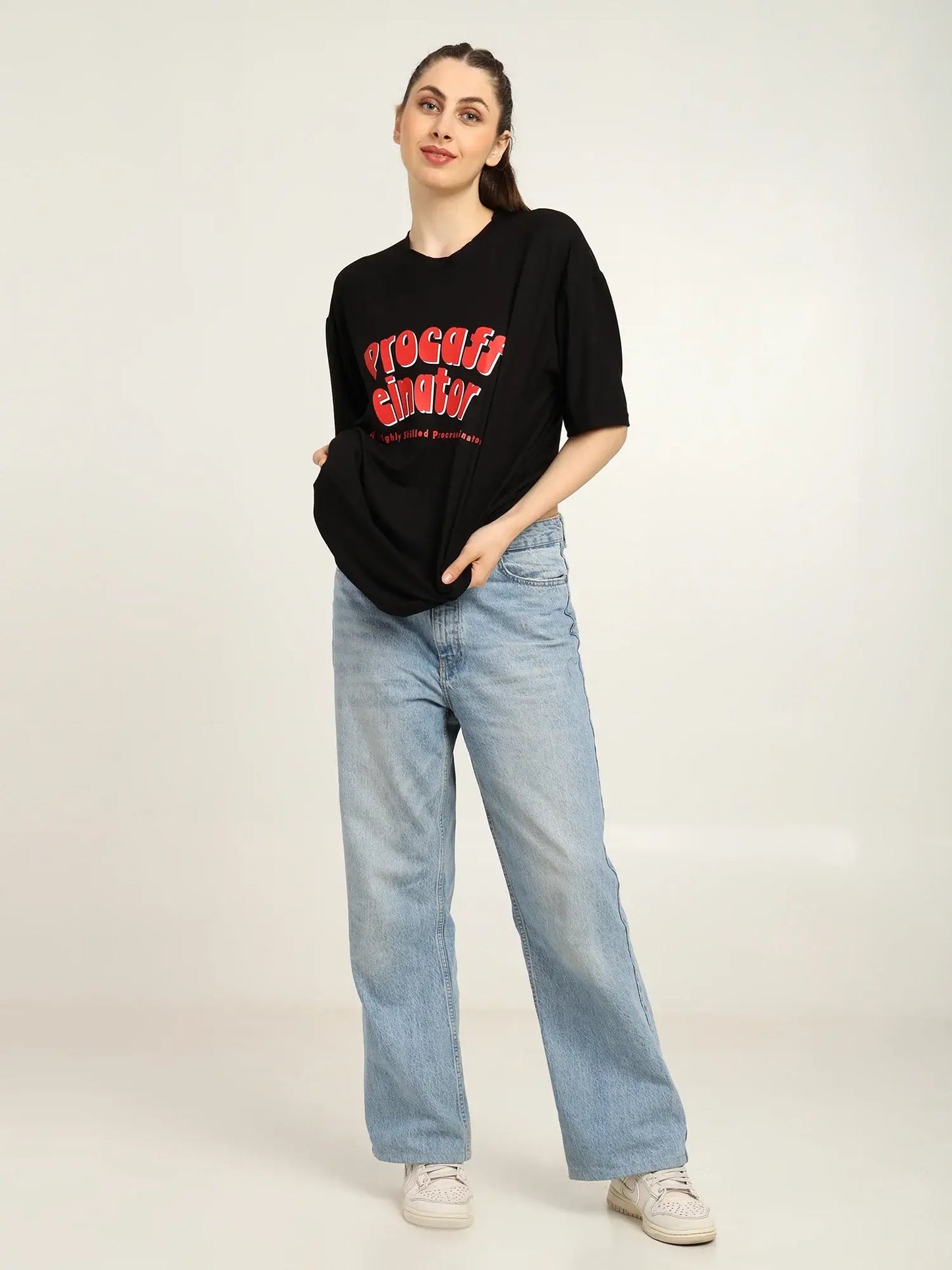 Person wearing a black t-shirt with red text and light blue jeans on a white background