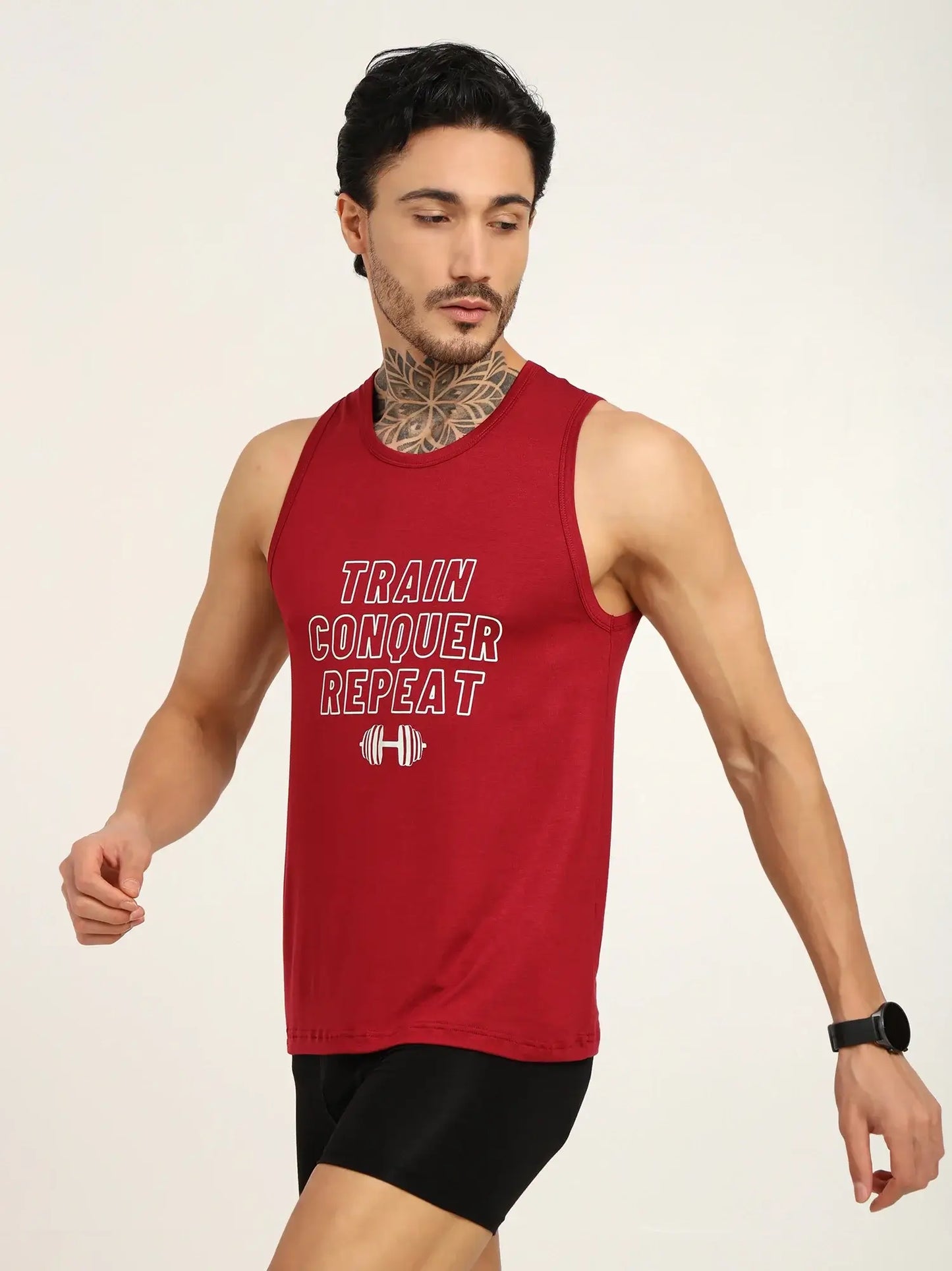 Model wearing a red tank top with 'Train Conquer Repeat' text, showcasing gym-ready athletic style.