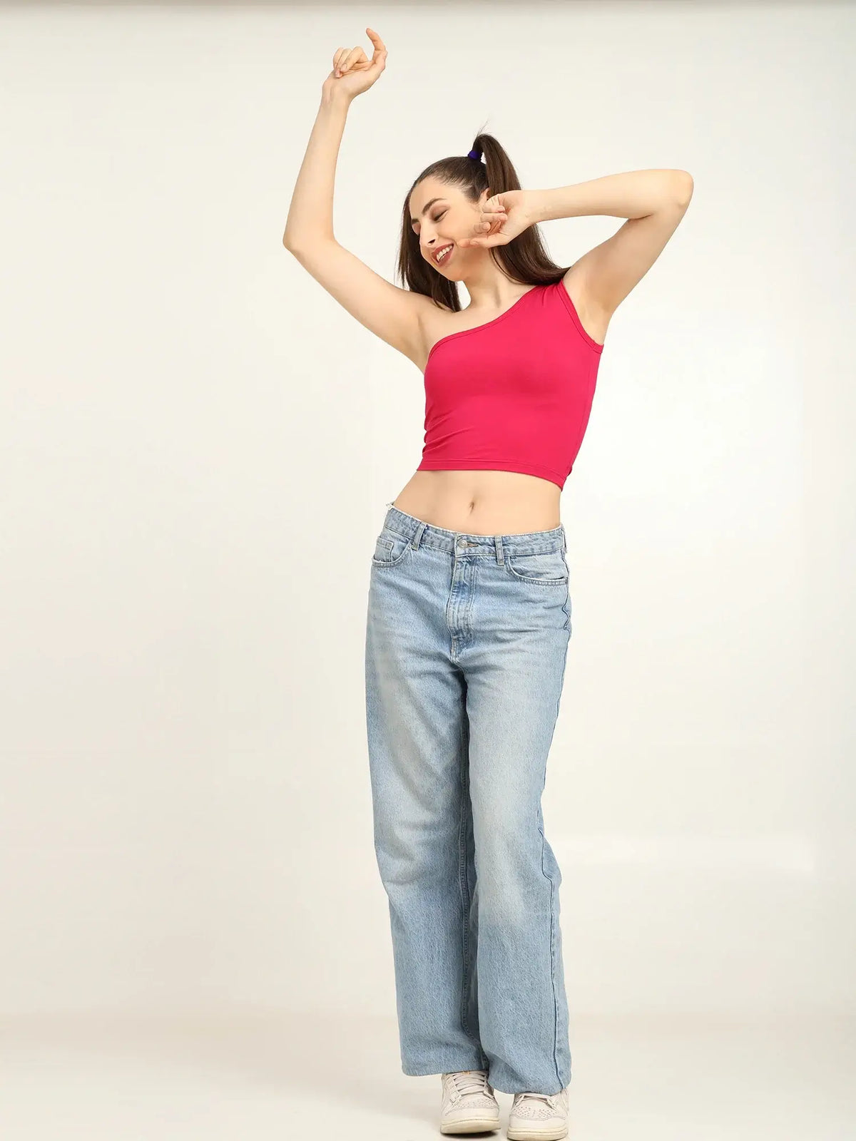 Model wearing a pink bamboo one shoulder top and wide-leg jeans, showcasing effortless Gen Z fashion.