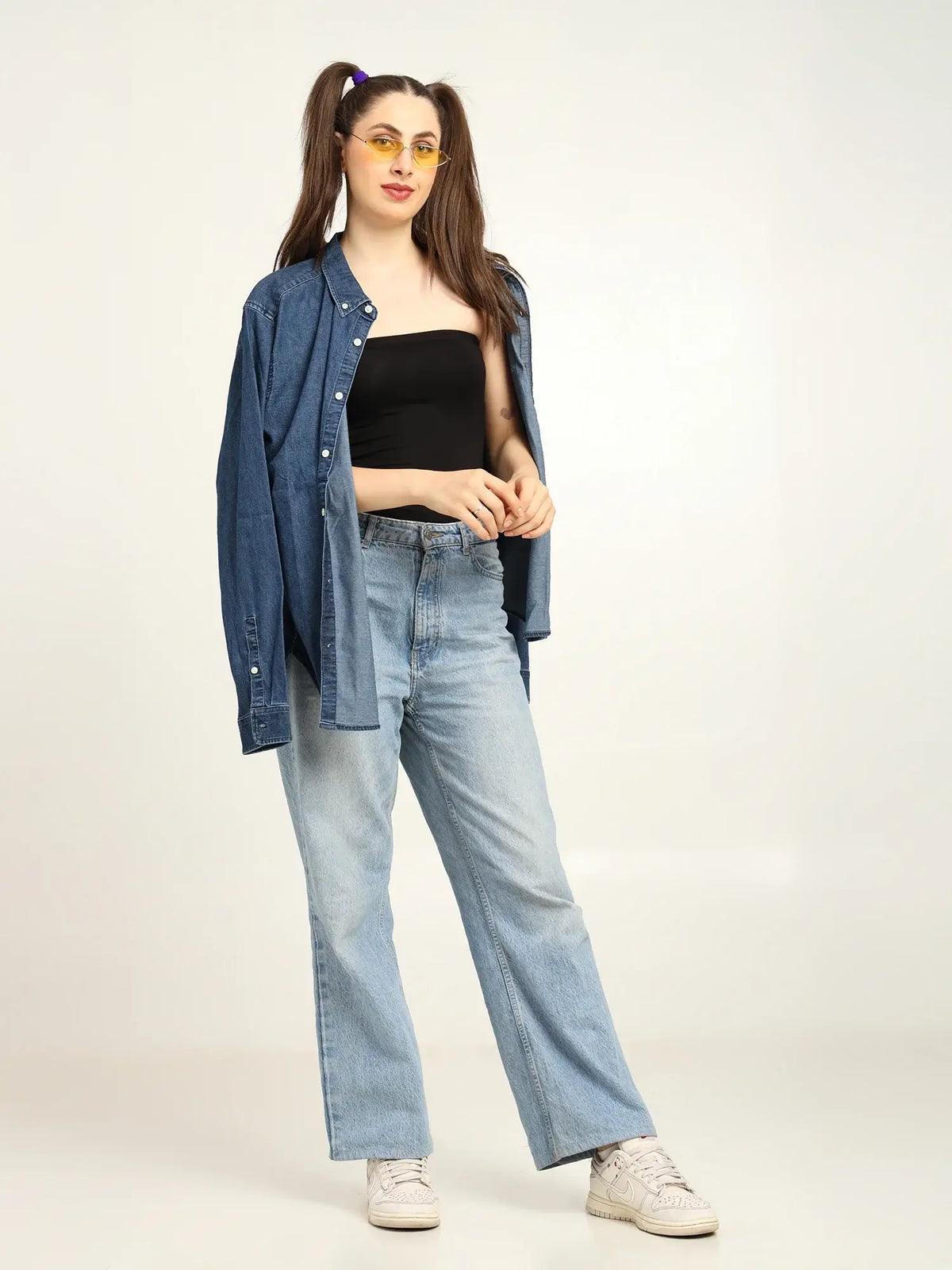 Gen Z woman wearing black bamboo tube top, denim shirt, and light jeans, showcasing effortless, sustainable fashion.