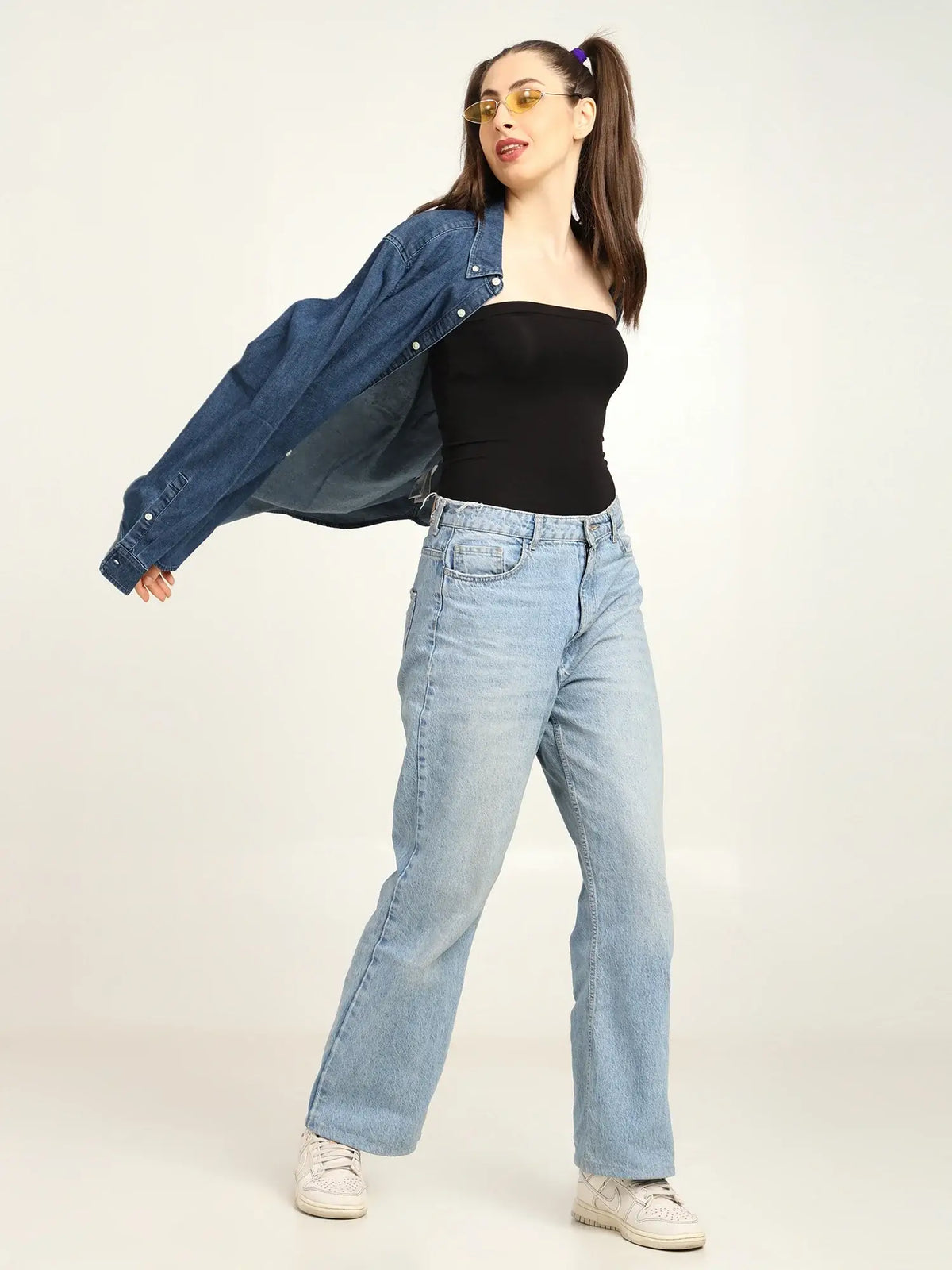 Gen Z woman in bamboo tube top and denim jacket, styled with light blue jeans, showcasing effortless fashion.